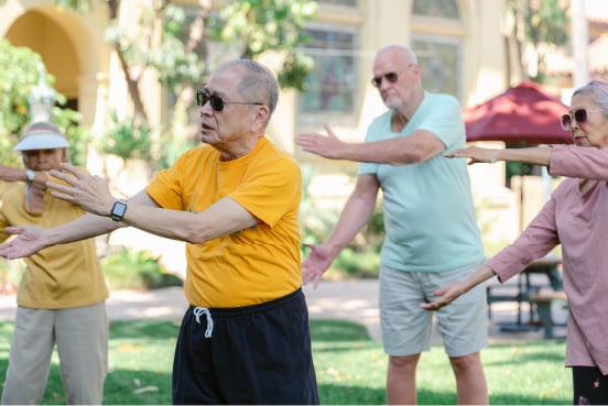 A group of men and women doing tai chi outdoors